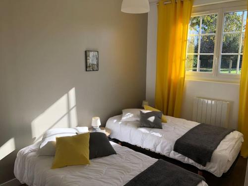 - 2 lits dans une chambre dotée de rideaux jaunes dans l'établissement AU FIL DE L EAU, à Menars