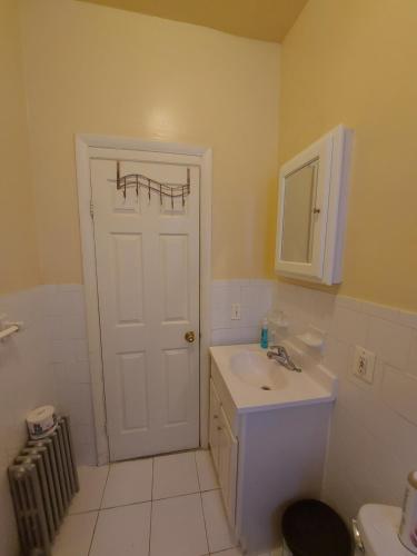 a bathroom with a white door and a sink at Crsytal Chateau Room Rental in Brooklyn