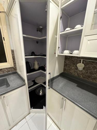 una pequeña cocina con armarios blancos y fregadero en Lovely High Quality Self Check-in Apartments شقق سلام بالدخول الذاتي en Medina