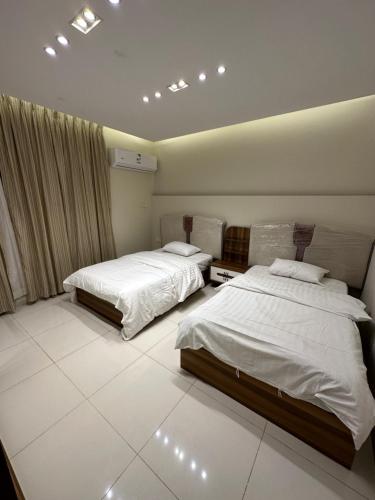 two beds in a room with white sheets at Lovely High Quality Self Check-in Apartments شقق سلام بالدخول الذاتي in Medina