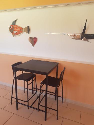 a table and two chairs and a wall with a fish on it at Eliopoli Beach Hostel & Restaurant in Tirrenia