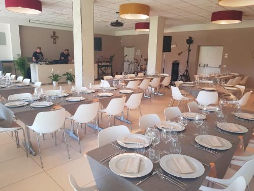 a large banquet hall with tables and white chairs at Eliopoli Beach Hostel & Restaurant in Tirrenia