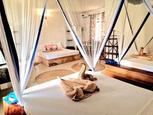 um quarto com duas camas e duas camas com cortinas em TIANDE Boutique Hotel em Pwani Mchangani