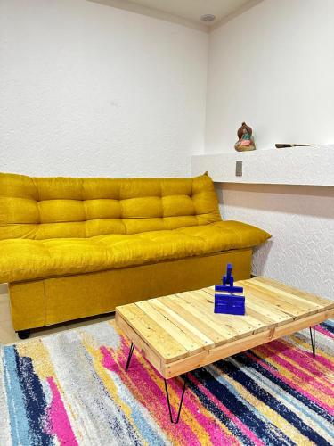 a yellow couch in a living room with a table at Rosa1B in Mexico City