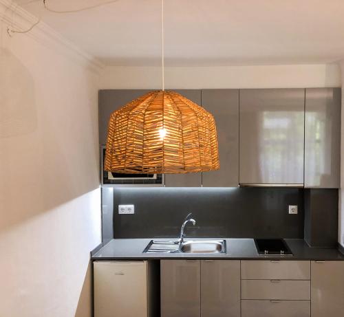 a kitchen with a sink and a pendant light at Hotel Apartamento Foz Atlantida in Monte Gordo