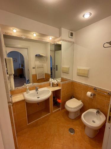 a bathroom with two sinks and a toilet and a mirror at Tristan casa vacanze a Roma in Casal Palocco