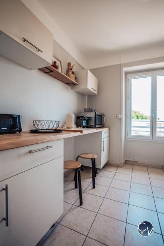 une cuisine avec des armoires blanches et une fenêtre dans l'établissement Superbe Appartement centre ville, à Pont-Saint-Esprit