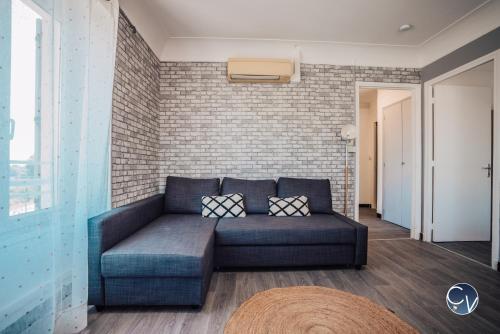 ein blaues Sofa in einem Zimmer mit Ziegelwand in der Unterkunft Superbe Appartement centre ville in Pont-Saint-Esprit