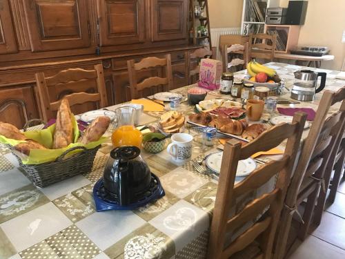 uma mesa com pequeno almoço de pão e frutas em Chambres d'hôtes "Là Je Ris" em Lagery