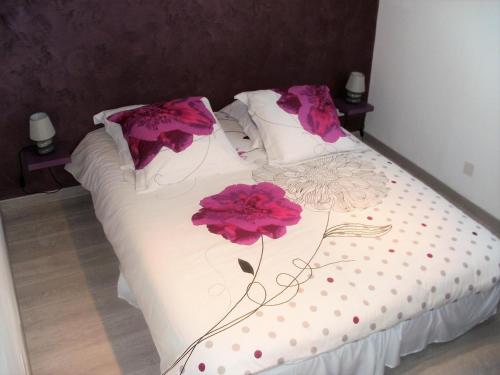 ein Bett mit zwei rosa Blumen drauf in der Unterkunft Gite de la buse in Sedan