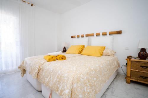 Dormitorio blanco con cama con almohadas amarillas en Reserva de Marbella, en Marbella