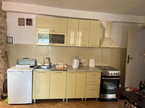 a small kitchen with white cabinets and a sink at Apartman Dado in Perast