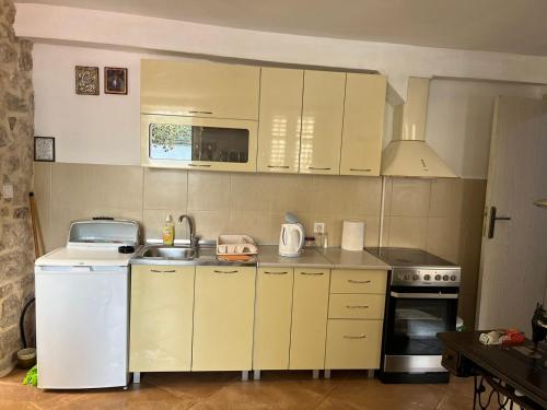 een kleine keuken met witte kasten en een wastafel bij Apartman Dado in Perast