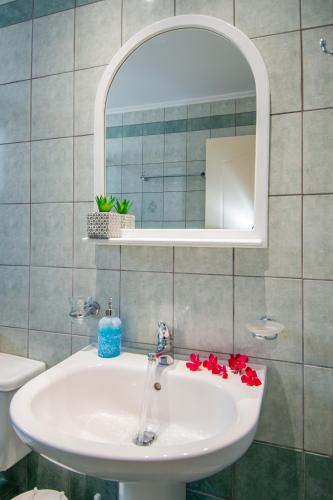 a bathroom with a white sink and a mirror at Spira Studios & Apartments in the Heart of Laganas in Laganas