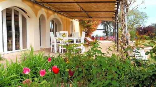 - une terrasse avec une table, des chaises et des fleurs dans l'établissement Appartement 5 personnes - Mas du Soleil, à Bagnols-sur-Cèze