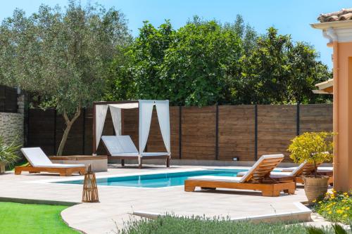 a backyard with a pool with lounge chairs and a fence at Villa Bella Donna Corfu in Corfu