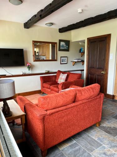 ein Wohnzimmer mit zwei roten Sofas und einem TV in der Unterkunft The Barn at Walker Ground Manor in Hawkshead