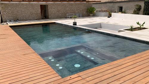 a large swimming pool with a wooden deck and a swimming pool at Gite de St Hilaire in Soubise