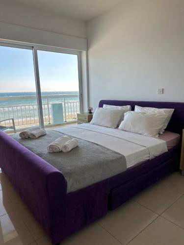a bedroom with a large bed and a large window at Sayers Beachfront Villa in Pervolia