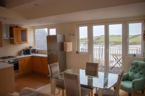 uma cozinha com uma mesa de vidro e uma cozinha com uma varanda em Beach Side Top Floor Property, Balcony & Sea Views em Newquay