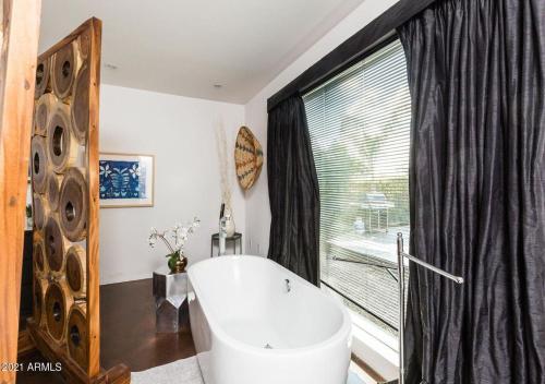 a bathroom with a tub and a large window at Designer 5 Bd Home, Fountain Pool, Spa, Game Patio in Phoenix