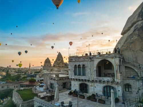 a group of hot air balloons flying over a building at Secret Hill Cave Suites in Goreme