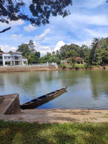 a boat sitting in the water next to a lake at Akkara Homestay in Kottayam