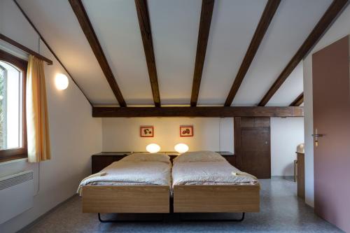 a bed in a room with a ceiling with beams at Parkhotel Emmaus - Casa Rustico in Ascona