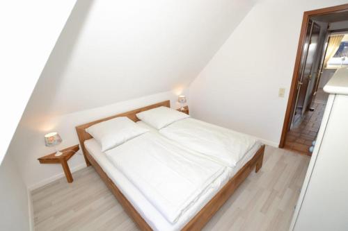 une petite chambre avec un lit blanc et une fenêtre dans l'établissement Wohnung-Jan, à Westerland