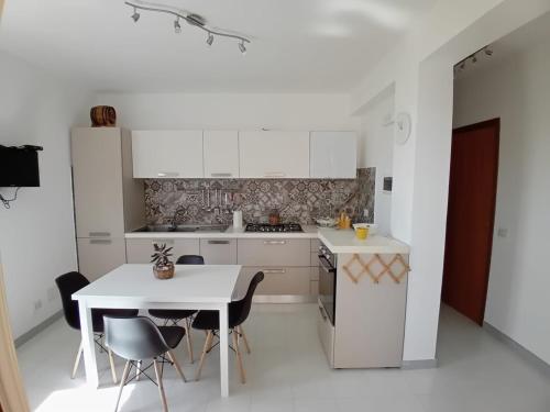 a white kitchen with a white table and chairs at Mamà Home-Casuzze in Villaggio Azzurro