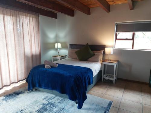 a bedroom with a bed with a blue blanket on it at Kragga Kamma Game Park in Port Elizabeth