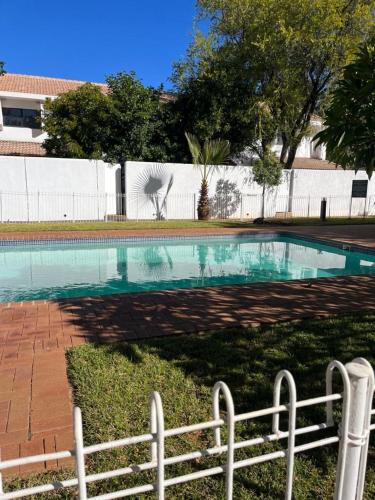 a swimming pool in a yard with a fence at Comfy Zone Apartment in Gaborone