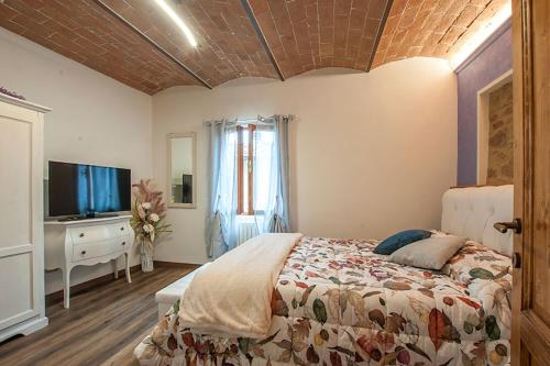 Schlafzimmer mit einem Bett und einem Flachbild-TV in der Unterkunft Affittacamere Il Bastione 27 in Volterra