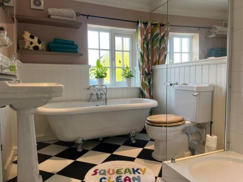 a bathroom with a tub and a toilet and a sink at Cosy cottage in town centre in Havant