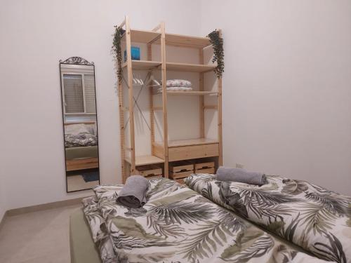 a room with a bed and a shelf and a mirror at נצר- צימר 