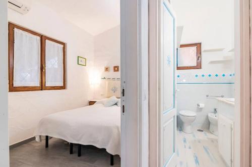 1 dormitorio con 1 cama y baño con aseo en RESIDENZE Coda Cavallo - Le Farfalle, en Capo Coda Cavallo