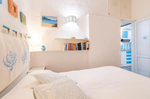 RESIDENZE Coda Cavallo - Le Farfalle في كابو كودا كافالو: غرفة نوم بيضاء مع سرير ورف كتاب