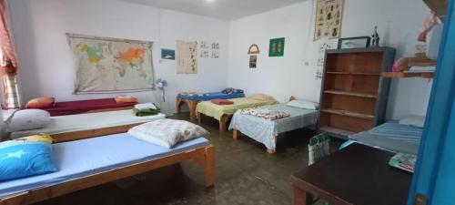 ein Zimmer mit mehreren Betten und Tischen in einem Zimmer in der Unterkunft Shkolla Hostel & Camping in Vuno