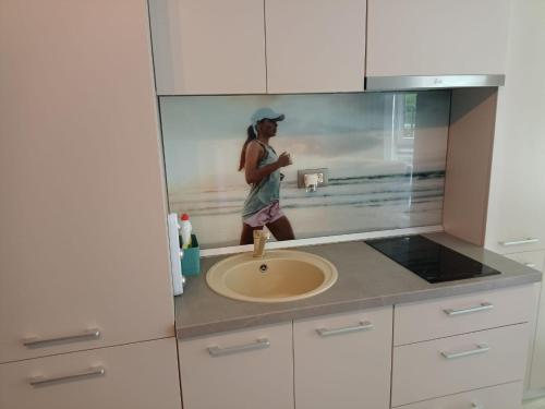 a woman standing in a kitchen with a sink at Studio Alezzi Beach Resort Ely in Năvodari