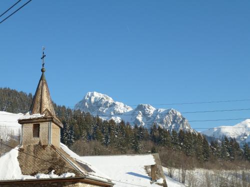 une église avec des montagnes enneigées en arrière-plan dans l'établissement Bernex(74) Appartement 4 personnes dans chalet vue imprenable, à Bernex