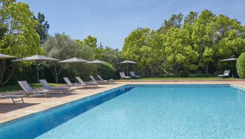 uma piscina com cadeiras e guarda-sóis em Golf Resort & Country Club Saint-Tropez em Saint-Tropez