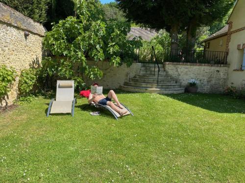 a woman laying in the grass reading a book at Gite les Merlettes in Abbecourt