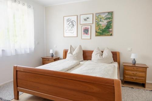 1 dormitorio con cama de madera con sábanas y almohadas blancas en Ferienwohnung `Pinie` mit Terrasse auf dem Bodanrück, en Radolfzell am Bodensee