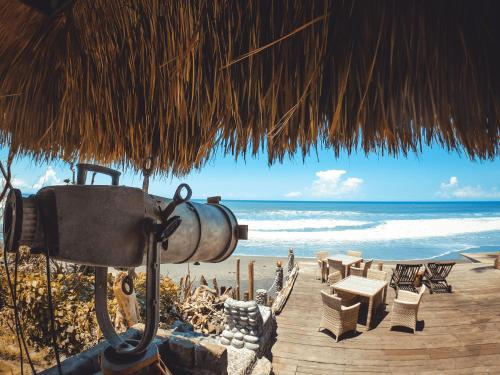 a beach with chairs and tables and a straw umbrella at Beachfront Villa Nixie and the Sea in Tabanan