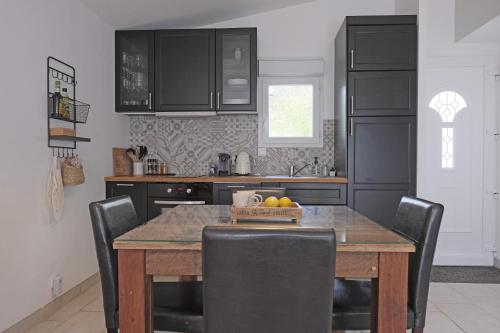 une cuisine avec une table en bois et des armoires noires dans l'établissement Maison de vacances Villa Cardabella, à Le Tignet