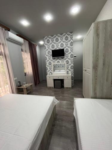 a bedroom with two beds and a tv on a wall at NAREMA FAMILY HOTEL Meghri in Meghri