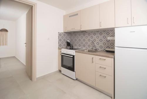 a kitchen with white cabinets and a white refrigerator at G&K House Garden in Messini