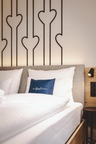 a bed with white sheets and a blue pillow on it at The Gast House Zell am See in Zell am See