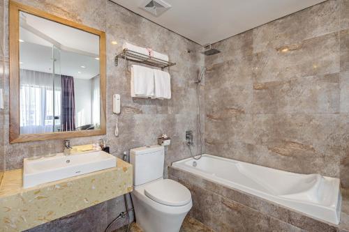 a bathroom with a toilet and a tub and a sink at Bliss Luxury Hotel & Spa in Da Nang