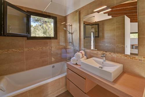 bagno con lavandino, vasca e specchio di Villa Chalet Porto Petro a Portopetro